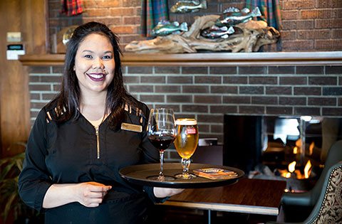 Woman smiling and holding a tray of beer