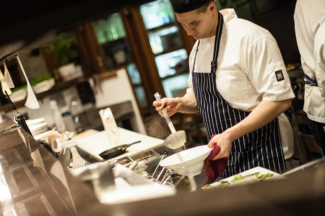 Chef filling a soup bowl