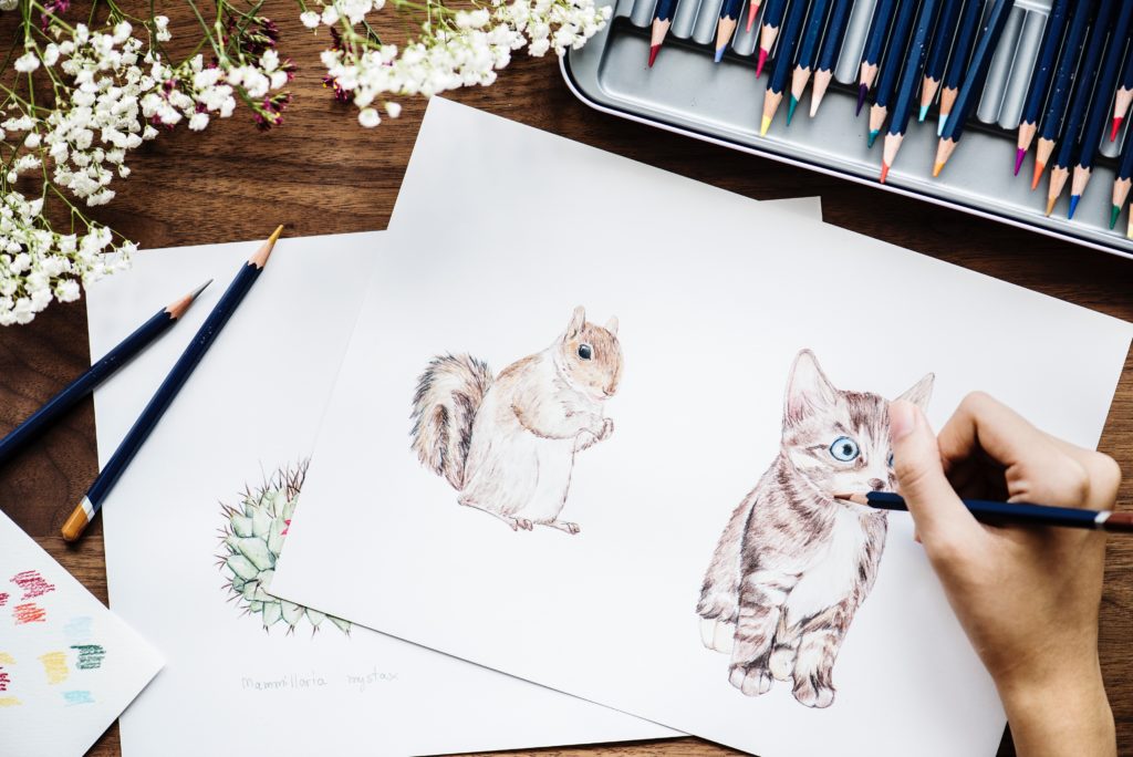 Hand creating realistic drawing of squirrel and kitten
